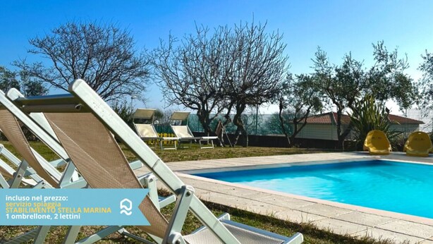Un área de piscina con sillones reclinables y un cielo azul despejado.