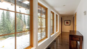 A hallway with large windows, wooden floors, and a framed picture on the wall.
