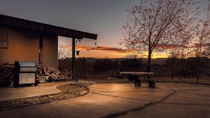 Un'area patio con una griglia barbecue, un muro in pietra e una panchina.