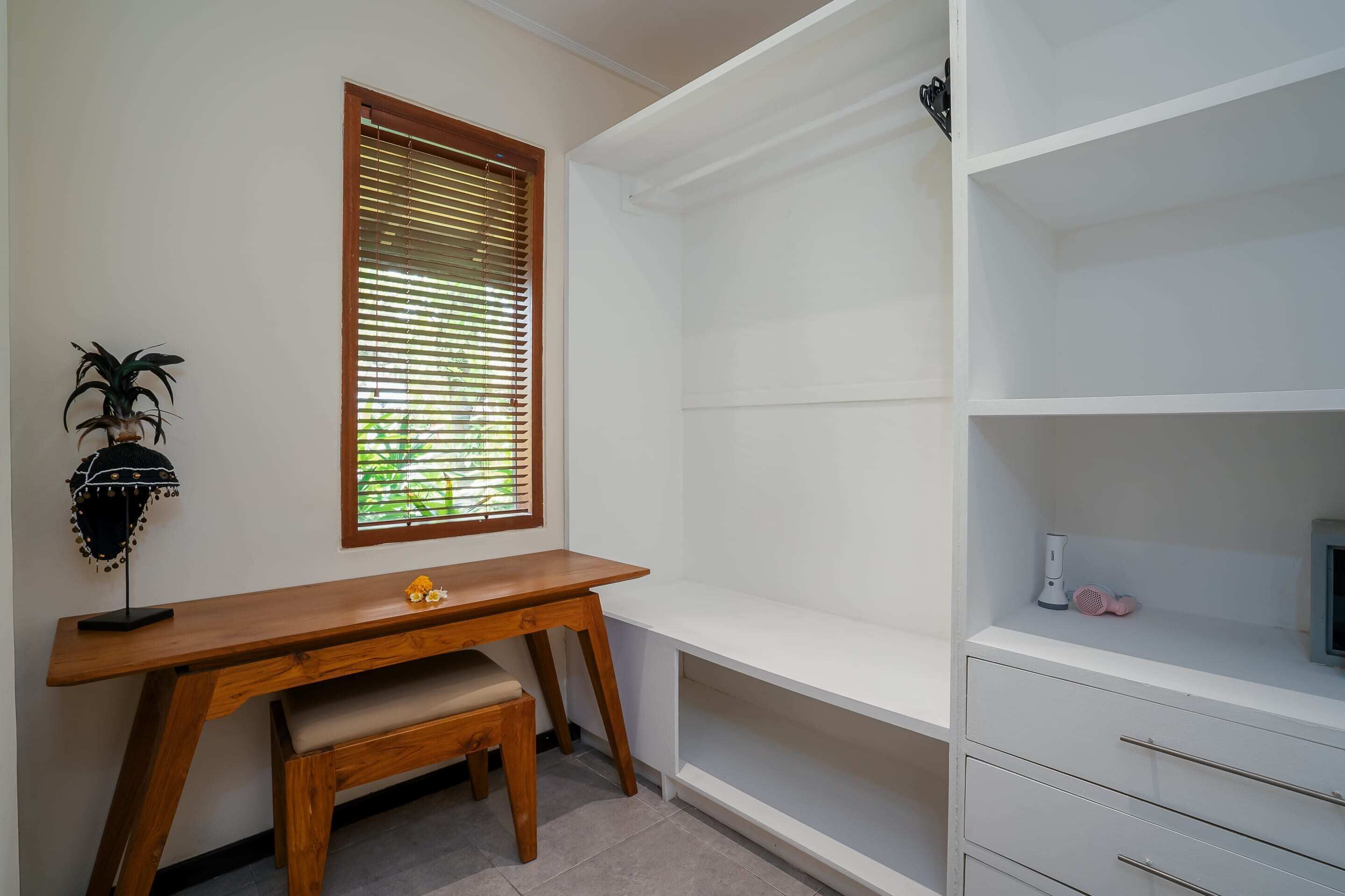 Une salle d’étude équipée d’un bureau en bois, d’un banc, d’une fenêtre avec des stores et d’une étagère blanche.