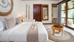 A neatly made bed with a white and gray bedspread, a wooden headboard, and a small wooden stool beside it. - Villa Alroda Ayun (Canggu)