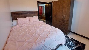 A bedroom with a bed, wooden wardrobe, and a ceiling light fixture. - Cozy 2-bedroom apartment in central location with WiFi, AC (Demerara-Mahaica)