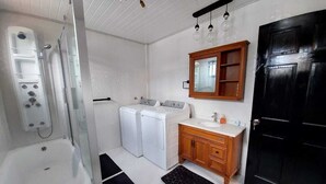A bathroom with a shower, two washing machines, a sink, and a mirror. - Cozy 2-bedroom apartment in central location with WiFi, AC (Demerara-Mahaica)