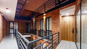 A modern interior with a brick facade, a wooden door labeled '20', and a metal railing overlooking a lower level.