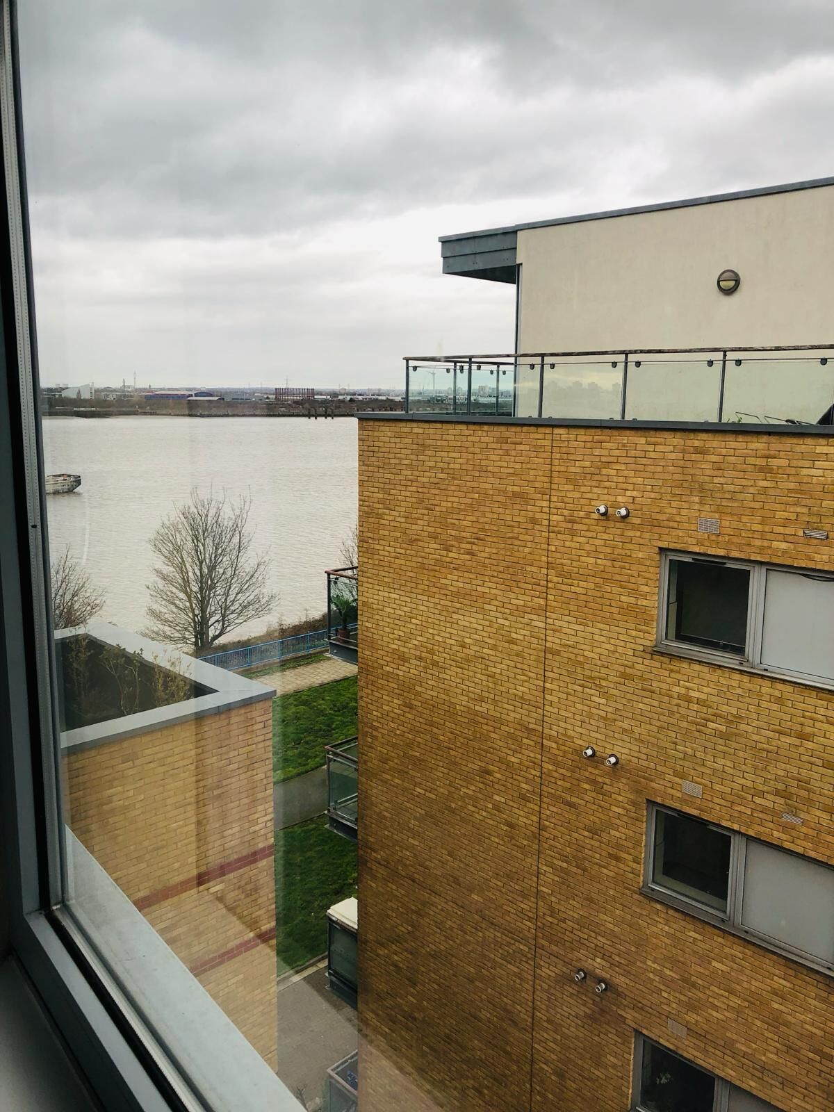Ein modernes Gebäude mit Backsteinfassade, großen Fenstern und Blick auf ein Gewässer.