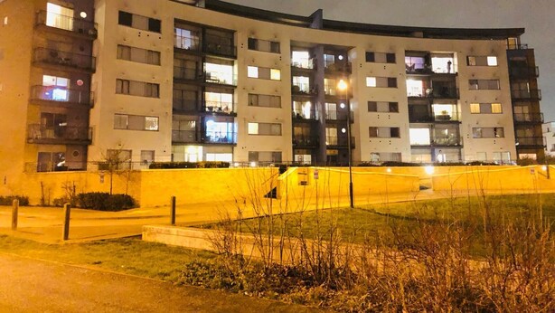 Un edificio residencial de varios pisos con balcones, techo plano y fachada bien iluminada.
