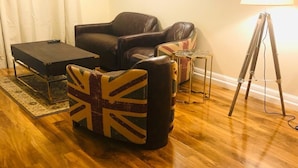 Una sala de estar con piso de madera, un sofá, una mesa de centro y una lámpara.
