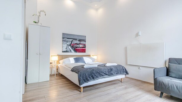 A modern bedroom with a bed, bedside tables, a wardrobe, and a painting on the wall.