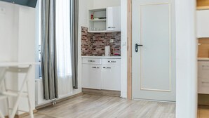 A modern kitchen with white cabinets, a brick backsplash, and a door with a gold frame.