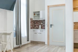 A modern kitchen with white cabinets, a brick backsplash, and a door with a gold frame.
