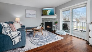 A living room with a fireplace, a television, and a view of the outdoors.
