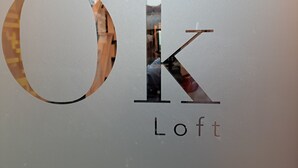 A logo with the letters "OK" and "Loft" on a textured wall.