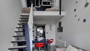 A modern interior with a staircase, a dining area, and a sofa.