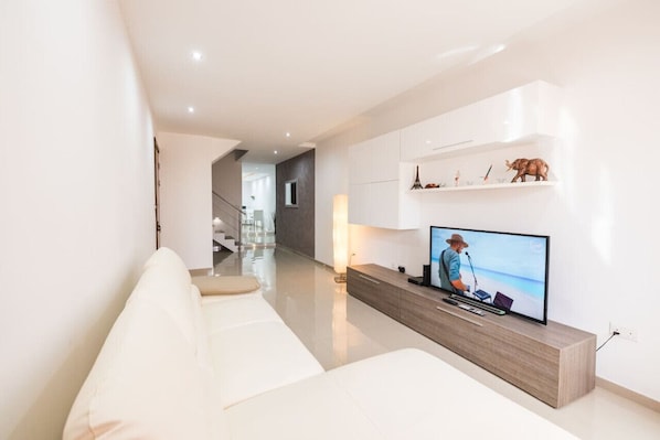 Un salon moderne avec un téléviseur à écran plat, un canapé et une console en bois.