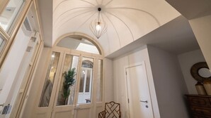 Una habitación con techo abovedado alto, un espejo grande y una silla de madera.