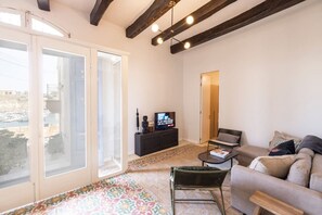 Ein Wohnzimmer mit einer Couch, einem Couchtisch, einem Fernseher auf einem schwarzen Schrank und einem Teppich mit Muster.