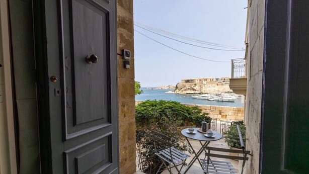 Un balcón con vista al mar y un edificio histórico.