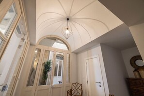 A room with a high arched ceiling, a large mirror, and a wooden chair. - Harbour Mansion 2 bedroom Maisonette (Birgu)