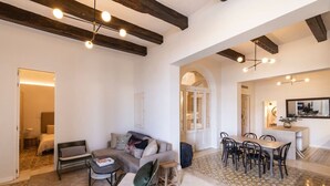 Amplia sala de estar con sofá, sillas, mesa de comedor y zona de cocina con mostrador y sillas.