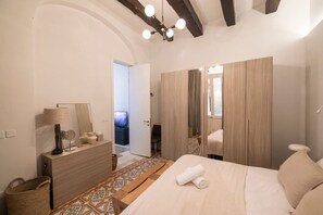 Ein Hotelzimmer mit einem Bett, einem Schminktisch, einem Spiegel und einem Fernseher im Hintergrund.