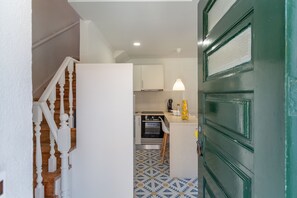A hallway leading to a kitchen with a patterned floor, a wooden staircase, and a green door. - Mouraria Lisbon Soul Apartments T2  5pax (Lisbon)