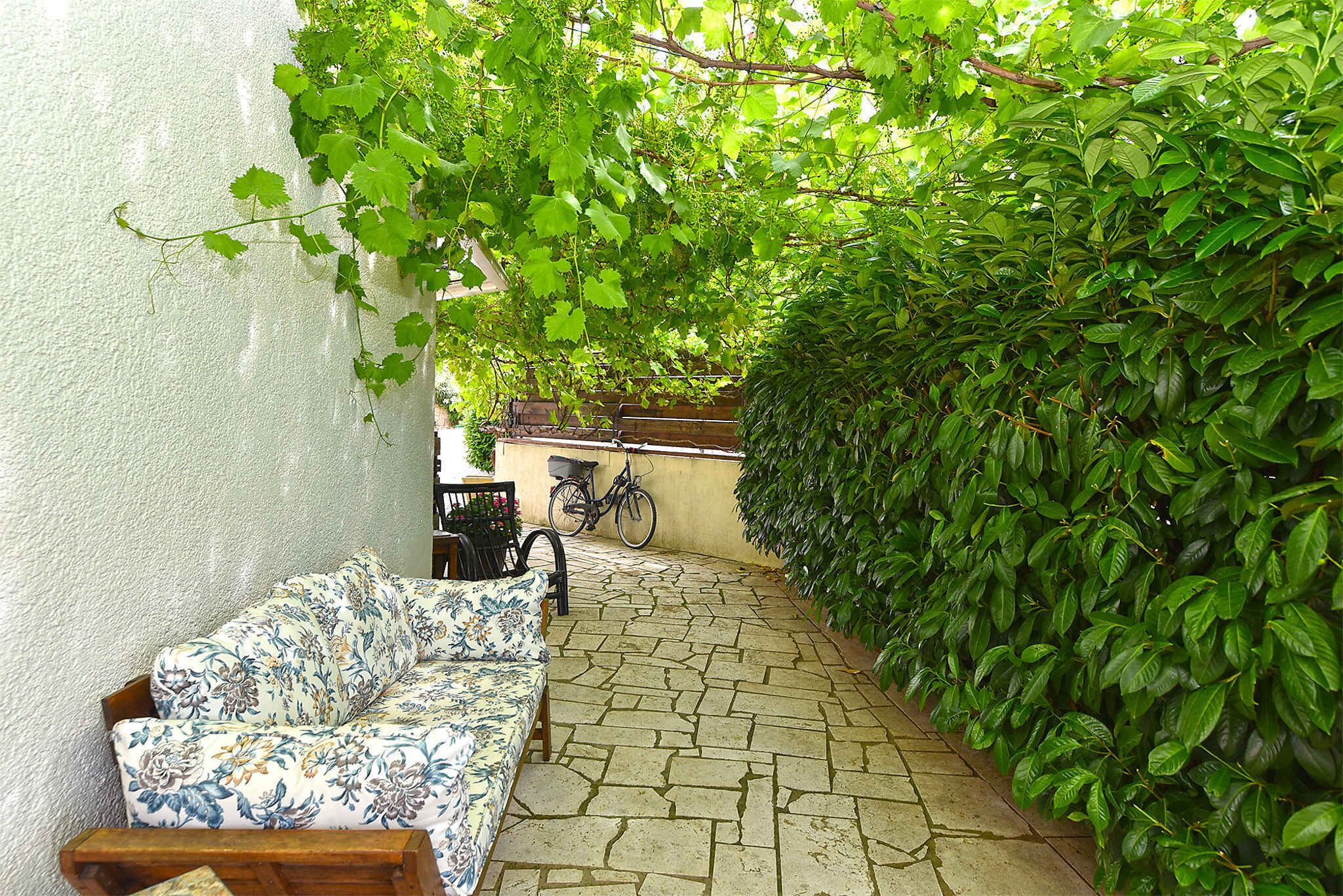 A stone-paved patio with a floral-patterned sofa and a bicycle.