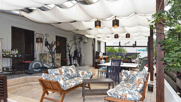 Un patio al aire libre con una zona de estar cubierta, una mesa y sillas.