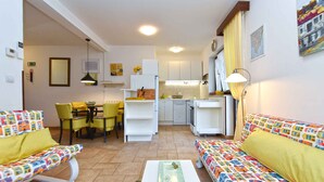 Un espacio habitable compacto con comedor, kitchenette y un conjunto de sofás.