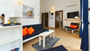 A modern living room with a sofa, a coffee table, a TV, and a chair. - Holiday apartment with pool, barbecue and fitness equipment for shared use (Barbariga)