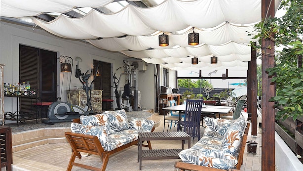 En udendørs patio med overdækket siddeområde, et bord og stole.