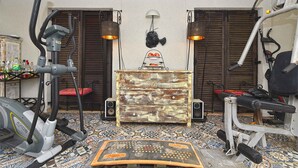 Uma academia doméstica com equipamentos de exercício, piso estampado e um aparador decorativo.