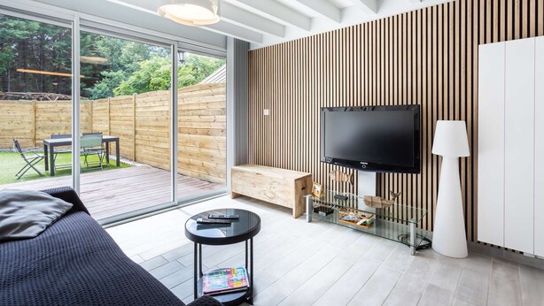 A modern living room with a large TV, a sofa, a coffee table, and a glass cabinet. - Maison mitoyenne proche du lac ! (BISCARROSSE)