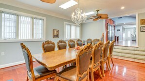 A dining room with a large wooden table and ornate chairs, a chandelier, and a ceiling fan.