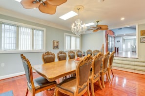 A dining room with a large wooden table and ornate chairs, a chandelier, and a ceiling fan.