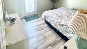 A bedroom with a bed, a ceiling fan, a television, and a door.