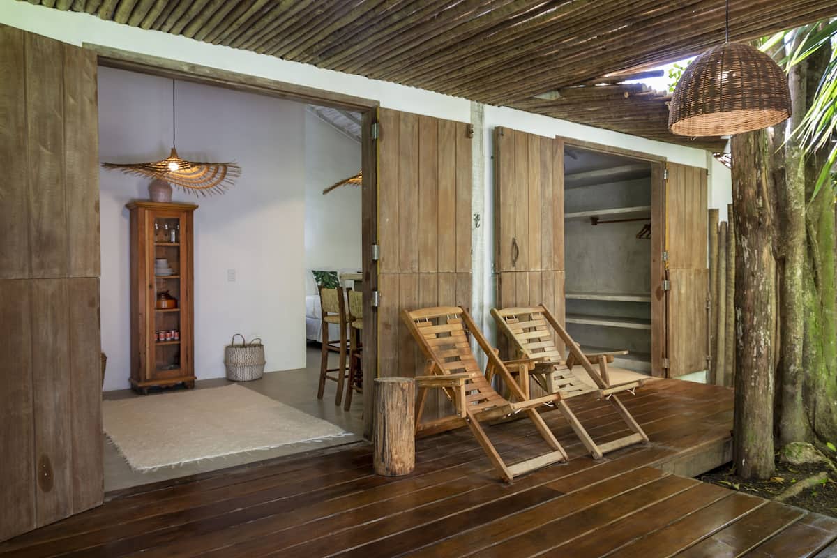 Une pièce au plancher de bois, dotée d’un luminaire suspendu en osier, de chaises en bois et d’un meuble contenant de la vaisselle.