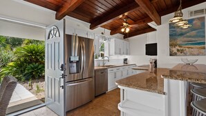 A modern kitchen with white cabinets, stainless steel appliances, and a wooden ceiling. - Sunset Vista | Private Dock, Dog-Friendly Home | My Beach Getaways (Pensacola Beach)