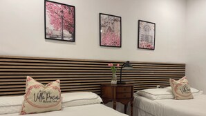 A hotel room with two beds, a wooden headboard, a nightstand with a lamp, and three framed pictures on the wall. - Villa Preciosa (Méntrida)