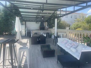 An outdoor patio with a dining area, a sofa, and a grill.