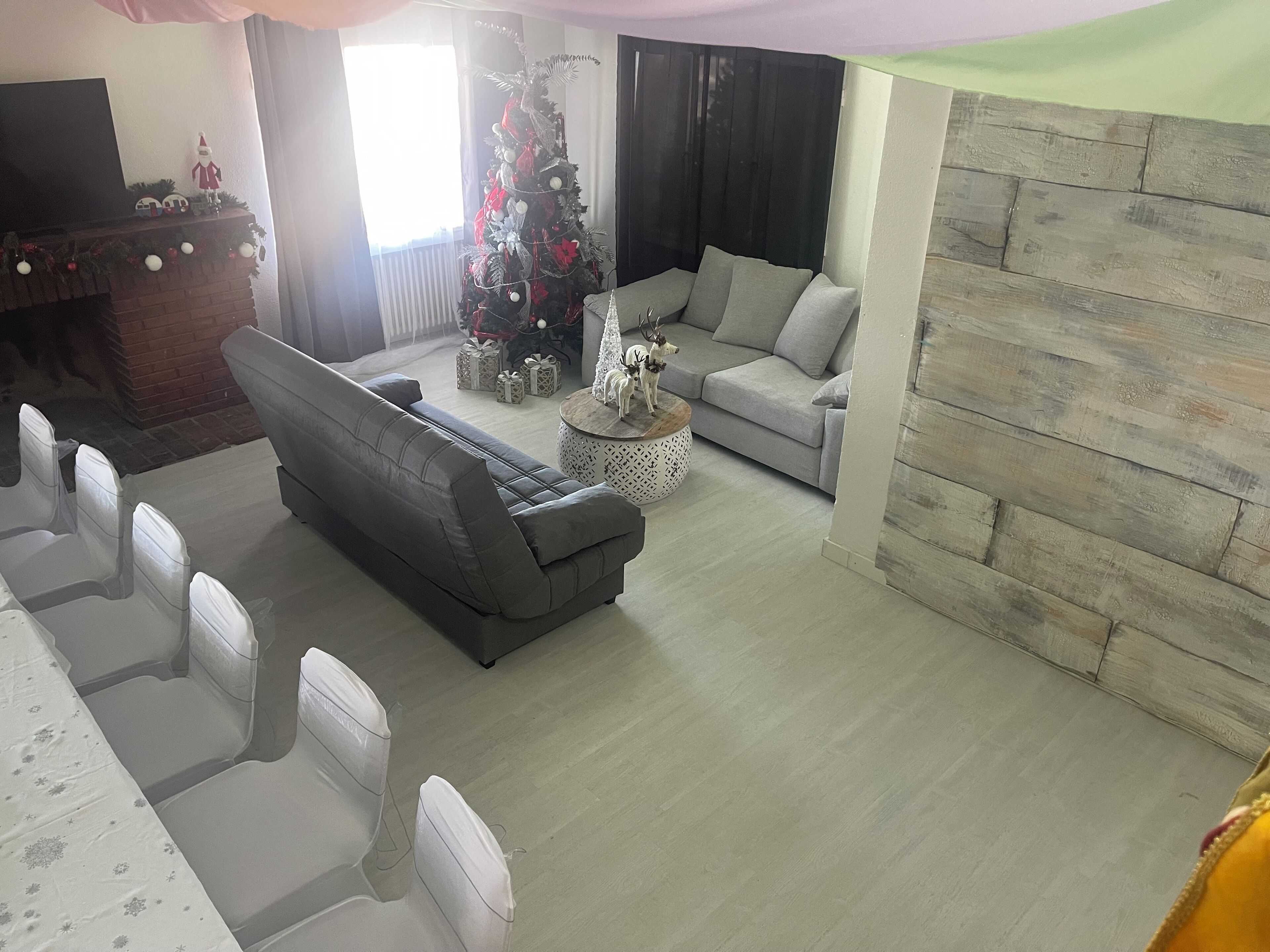 A living room with a grey sofa, a grey armchair, a round coffee table, and a Christmas tree.