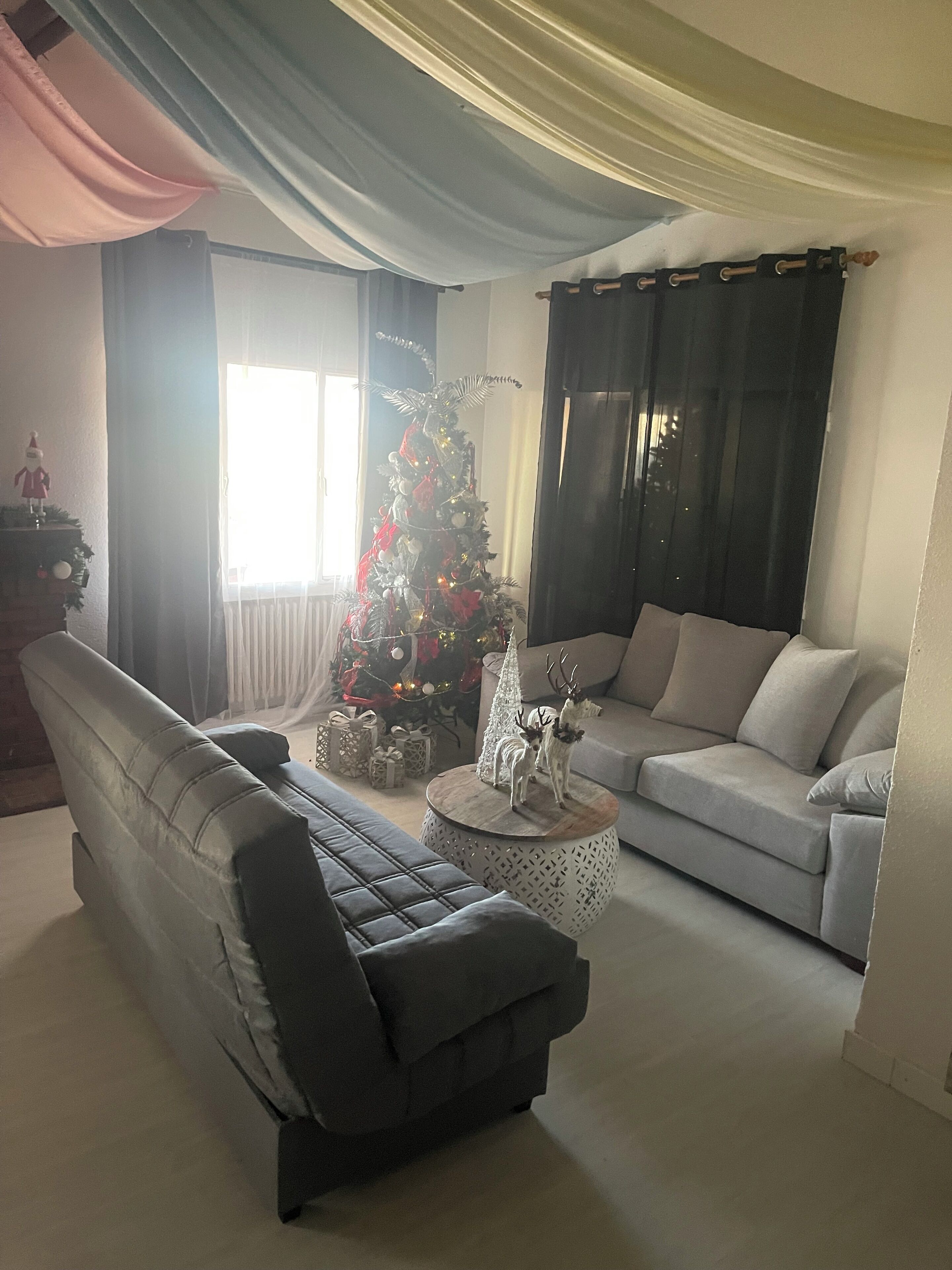 A living room with a sofa, a coffee table, and a Christmas tree.