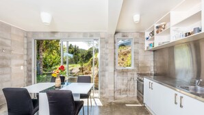 A modern kitchen with a large island, white cabinetry, and a view of the outdoors. - Secluded Haven with Stunning Hokianga Harbour Views (Omapere)
