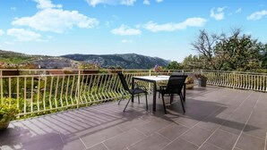 A terrace with a table and chairs, a railing, and a view of mountains. - Amazing apartment in Grizane with WiFi (Grizane)