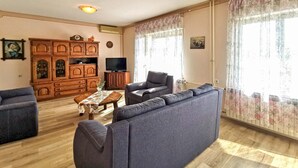 A living room with a sofa, a television, wooden cabinets, and a table with a vase. - Amazing apartment in Grizane with WiFi (Grizane)