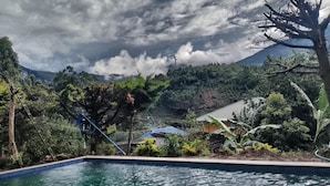 A pool area with a view of a mountain and lush greenery. - Nexstay Ministers Mansion (Devikolam)