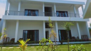 A modern two-story building with balconies, large windows, and a well-maintained lawn with small plants. - THELOCAL AREGULING  (Kuta)