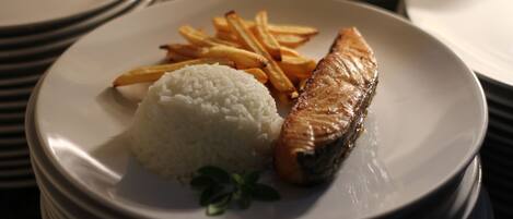 Un plato de arroz blanco, un trozo de salmón a la parrilla y papas fritas.