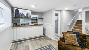 Una cocina moderna con isla integrada, un comedor con mesa de madera y una escalera que lleva a un nivel superior.