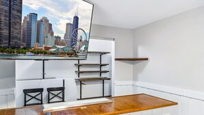 Una habitación de hotel moderna con un escritorio de madera, un ventanal con vistas a la ciudad y estanterías empotradas.