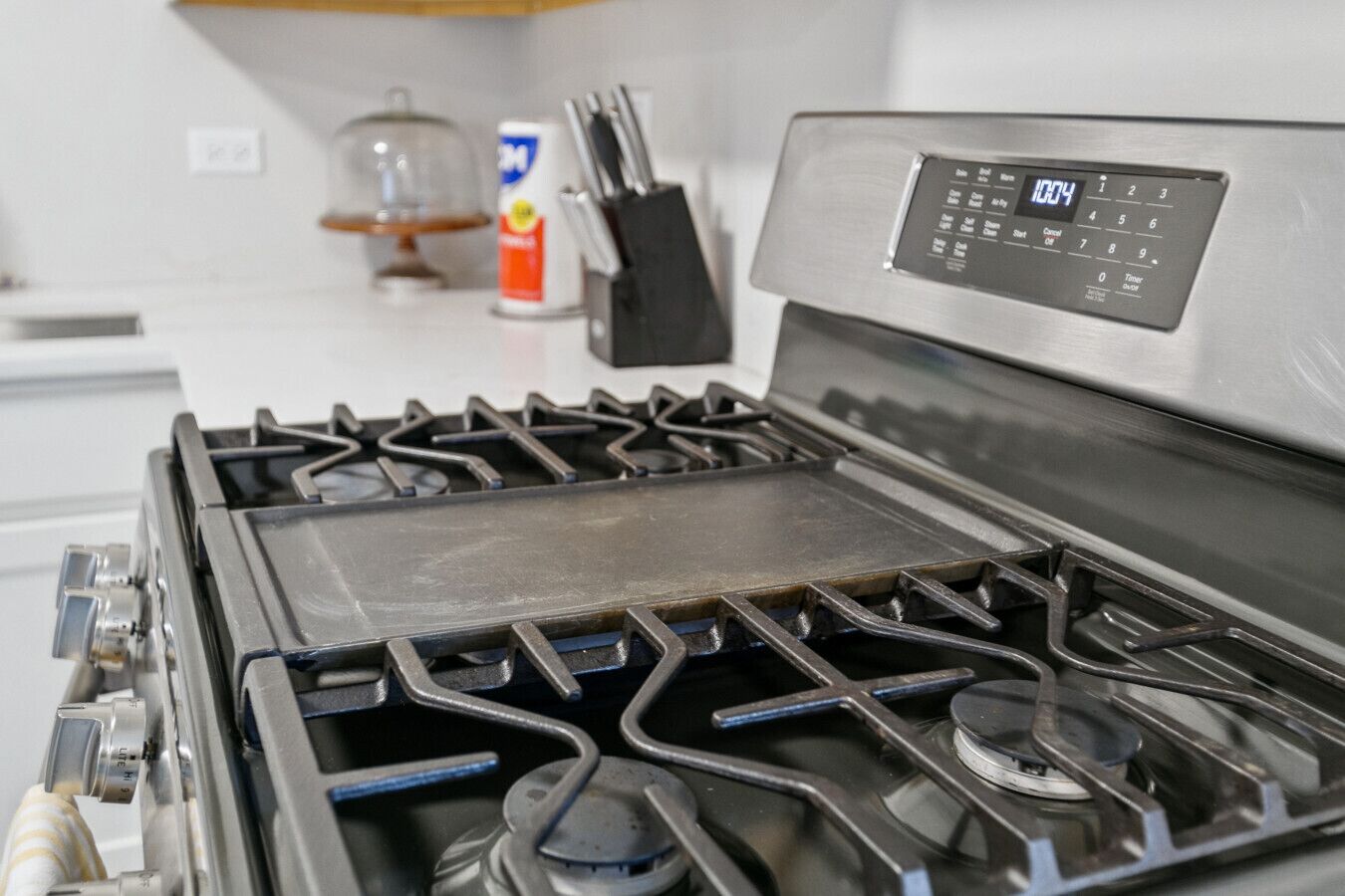A kitchen with a stove, a digital control panel, and a can of spray cleaner on the counter.